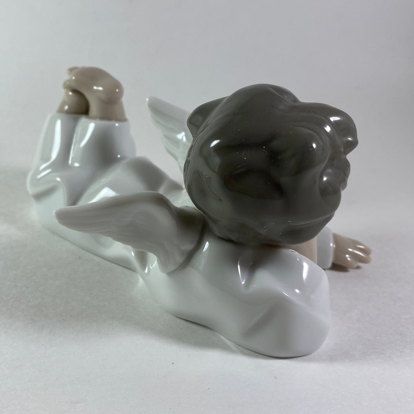 Lladro angel figurine in glossy porcelain lying down with legs crossed 4541