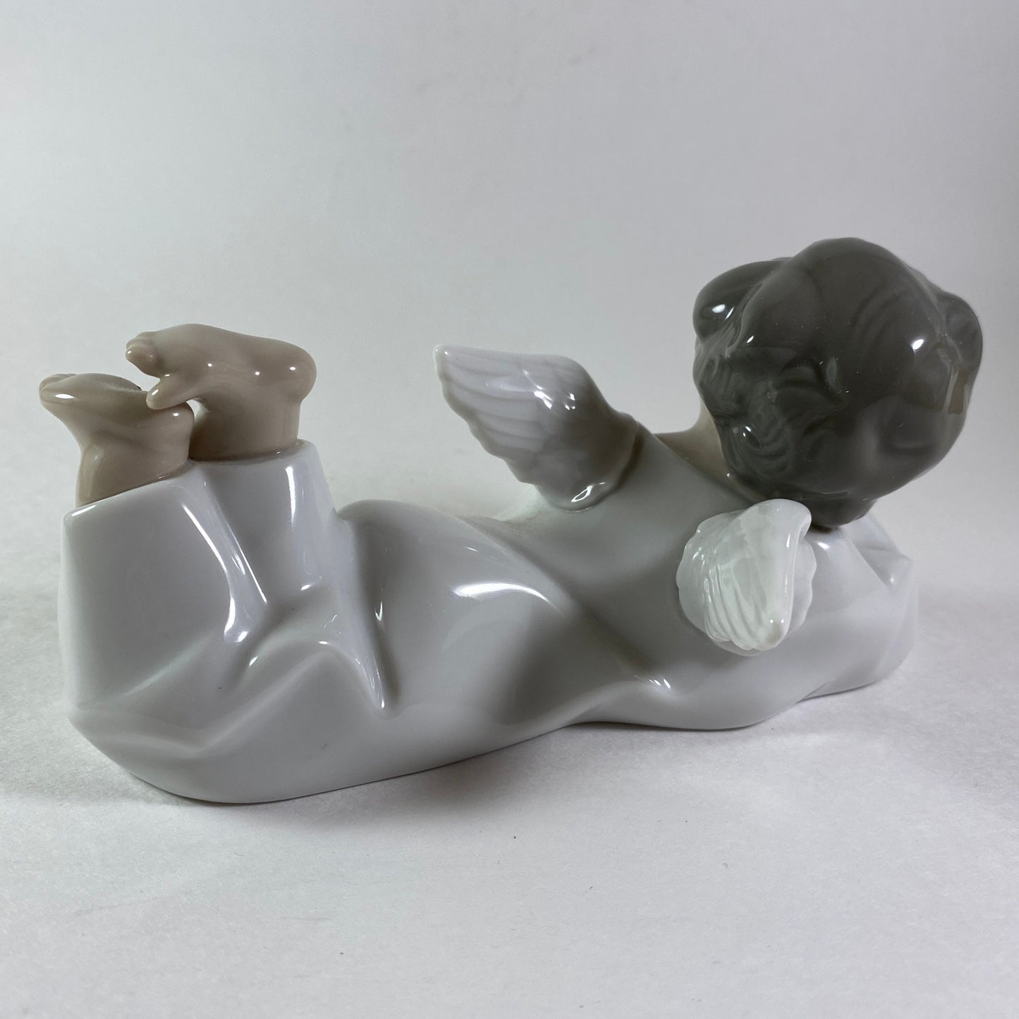 Lladro angel figurine in glossy porcelain lying down with legs crossed 4541