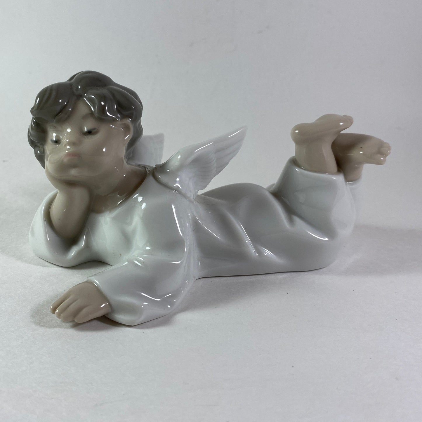 Lladro  angel figurine in glossy porcelain lying down with legs crossed 4541